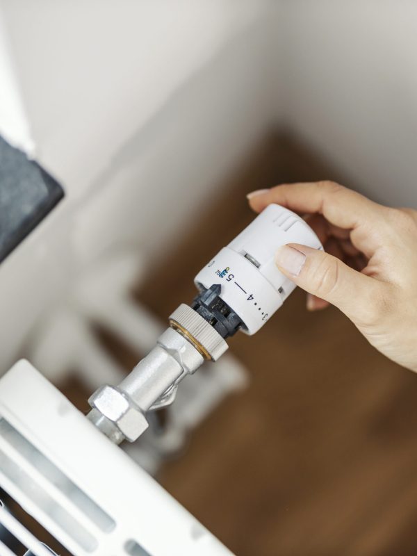 Hand of a woman screwing valve and saves heating.