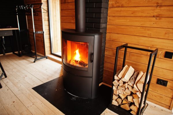 Fireplace with woods in modern wooden house.