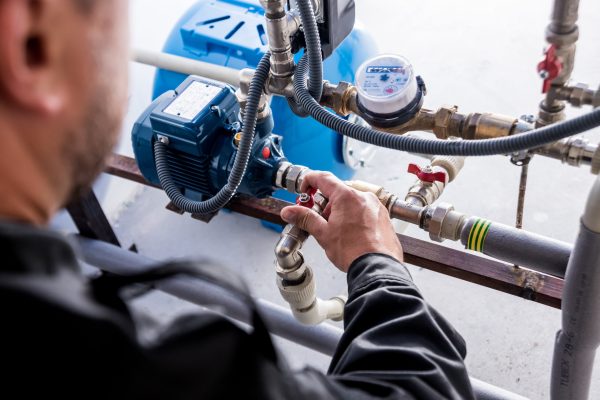 Technician checking water system nodes. Modern Industrial background.