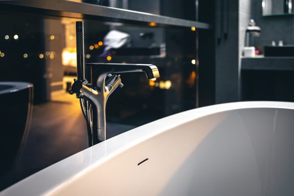 Steel faucet in the interior of a modern bathroom with a window overlooking the night city.